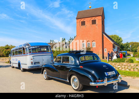 SYLT ISLAND, GERMANY - SEP 10, 2016: classic black Mercedes Benz limousine and bus parking in front of a church in Wenningstedt  Stock Photo