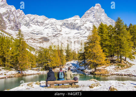 Lago Blu (Blue Lake) with the Cervino Mountain (aka 'Matterhorn' in Switzerland) behind, Aosta Valley, Italy. Friends sit on a bench. Stock Photo