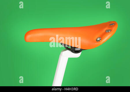 Orange bike saddle isolated on green background Stock Photo