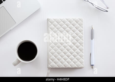 White office desk with a part of laptop, glasses, coffee Stock Photo