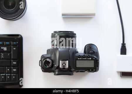 White desk with a professional camera and accessoires on it Stock Photo