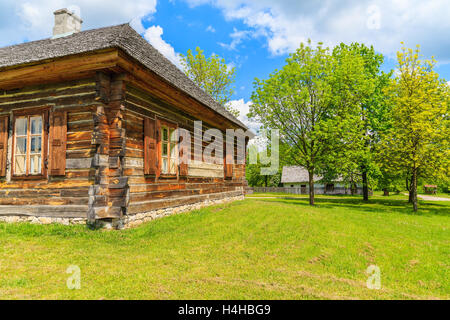 TOKARNIA VILLAGE, POLAND - MAY 12, 2016: An old rustic cottage house on green meadow in open air museum in Tokarnia village, Pol Stock Photo