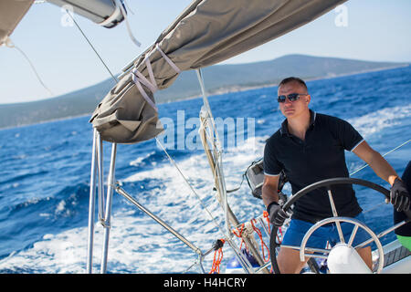 Young sailor skipper manages sailing vessel during regatta race in the open sea. Stock Photo