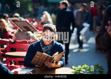 Young handsome man looking at the menu outdoors Stock Photo