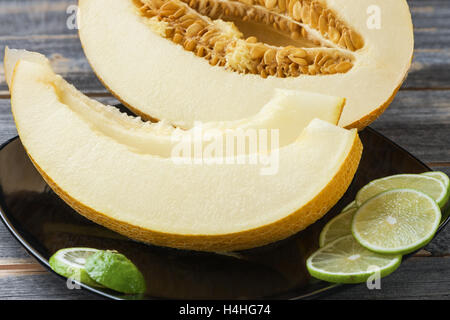 Ripe melon and lime on a black plate  old boards Stock Photo