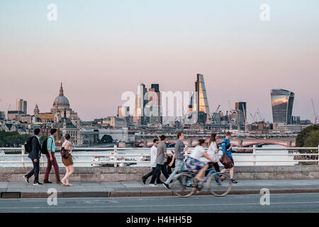 People walking and cycling over Waterloo Bridge in London in the evening, with a cityscape backdrop Stock Photo