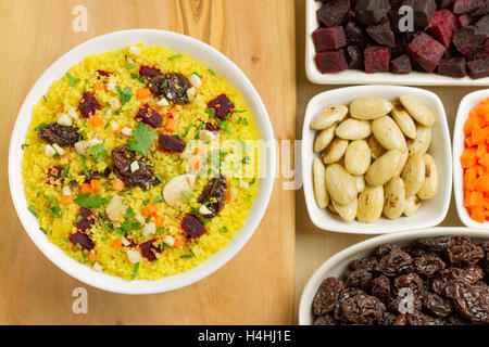 Vegetarian couscous in a white bowl with ingredients on a wooden table Stock Photo