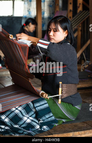 Women weaving traditional fabrics on backstrap looms in Thimphu, Bhutan Stock Photo