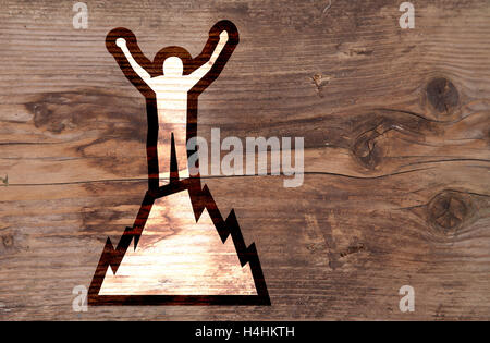 Illustration of man on top of mountain on brown wooden background Stock Photo