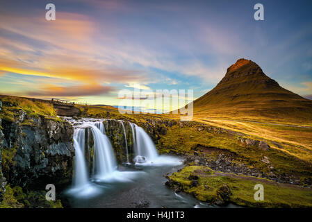 Summer sunset over the famous Kirkjufellsfoss Waterfall with Kirkjufell mountain in the background in Iceland. Long exposure. Stock Photo