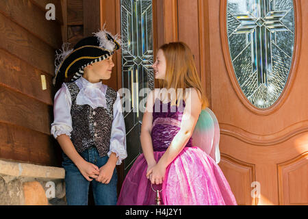 Children dressed up in Halloween costumes on the front porch waiting to go trick or treating Stock Photo