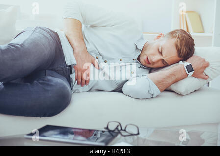 Sick man lying on the couch Stock Photo