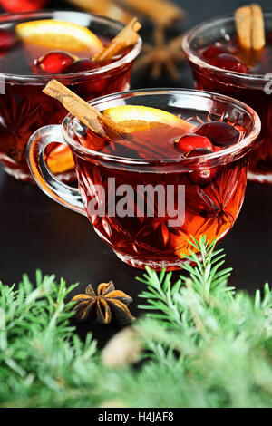 Red Christmas punch / drink with cinnamon, orange slices, anise and fresh cranberries over a dark background. Stock Photo