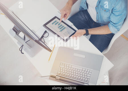 Hardworking man doing his work on different devices Stock Photo