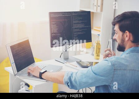 Handsome programmer using laptop in a cozy office Stock Photo