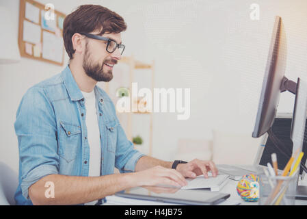 Delighted programmer in glasses using a computer Stock Photo