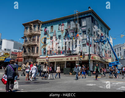 Busy street scene: Artists touch up murals on apartment building above New Sun Hong Kong Restaurant in San Francisco Chinatown. Stock Photo