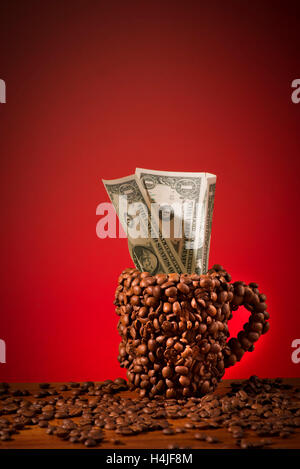 The coffee cup which is made with coffee beans.Dollar bills in the cup. Stock Photo