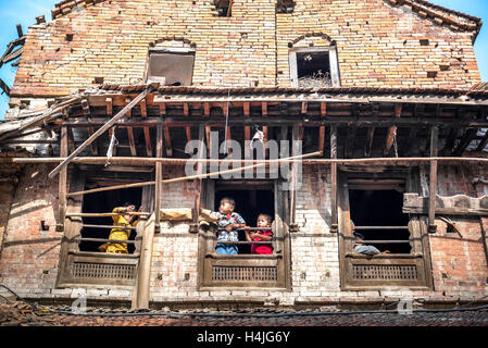 Children playing at the windows of a house destroyed by the 2015 earthquake in Bhaktapur, Nepal. Stock Photo
