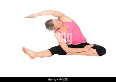 Barefoot fit young woman with a healthy toned muscular body doing yoga exercises stretching her arm and leg in a graceful positi Stock Photo