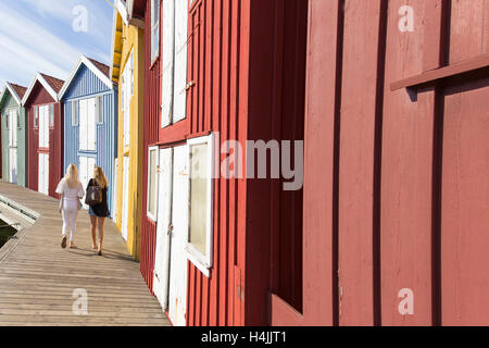 Two women walking next to fishing huts, Smögen, Bohuslän, West Sweden, Sweden Stock Photo