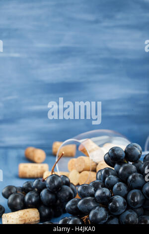 Branch of purple grape and wine corks on the table with glass and bottle on background Stock Photo