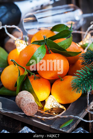 Holiday concept: fresh tangerines, cork, glass, champagne, candles and garlands Stock Photo