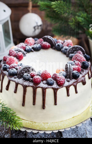 Delicious homemade cake decorated with chocolate, cookies and fresh berries on festive background Stock Photo