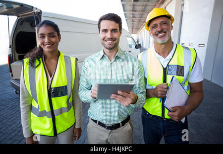 Manager and warehouse workers standing with digital tablet and clipboard Stock Photo