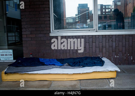 The foam mattress and belongings of a rough sleeper left in a doorway Stock Photo