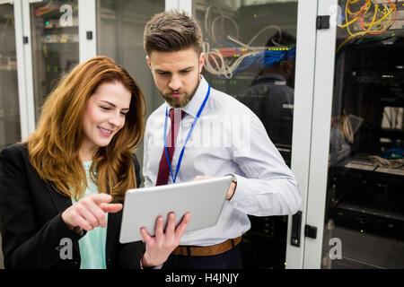 Technicians using digital tablet while analyzing server Stock Photo