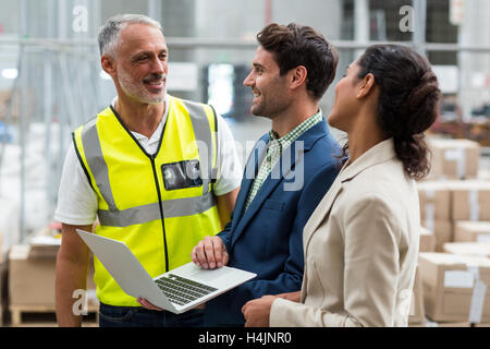 Warehouse managers and worker discussing with laptop Stock Photo