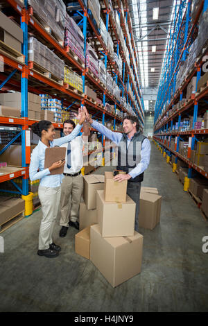 Happy warehouse workers giving high five Stock Photo