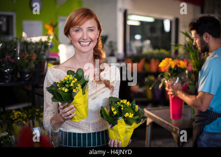 Woman holding flower bouquet while man working in the background