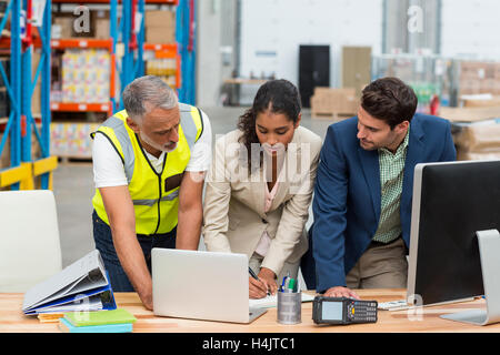 Warehouse managers and worker discussing with laptop Stock Photo