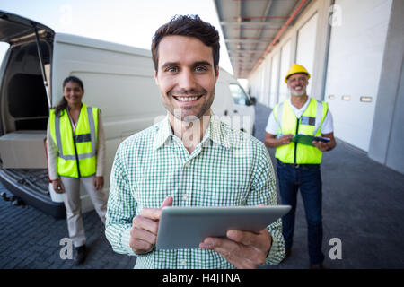 Portrait of manager using digital tablet and workers standing in background Stock Photo