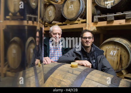 Owen, Germany. 13th Oct, 2016. Christian Gruel (l) and his grandson Immanuel Gruel stand amidst whisky barrels in the whisky barrel cellar of spirits distillery Gruel in Owen, Germany, 13 October 2016. PHOTO: MARIJAN MURAT/dpa/Alamy Live News Stock Photo