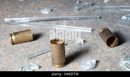 Empty brass from a handgun surrounded by broken glass on concrete Stock Photo