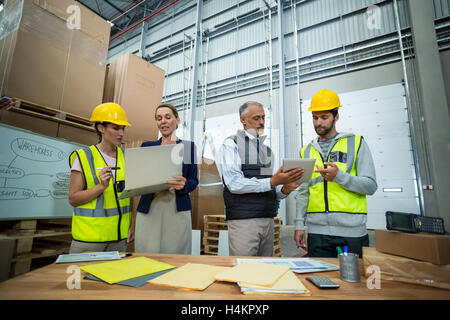 Warehouse managers and workers discussing with laptop and digital tablet Stock Photo