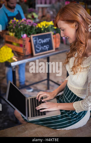 Female florist sitting and using laptop Stock Photo