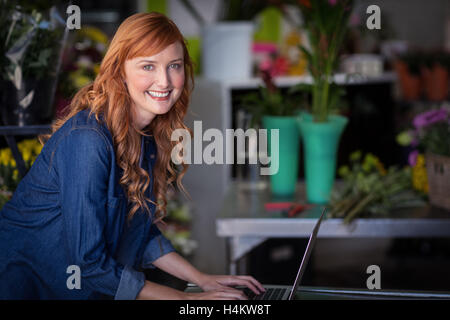 Smiling florist using laptop in flower shop Stock Photo