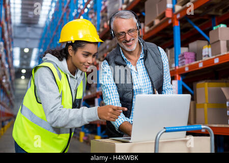 Warehouse manager and female worker using laptop Stock Photo