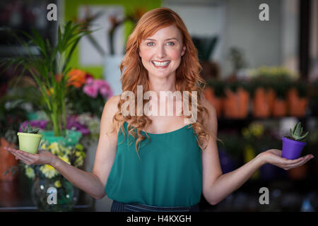 Female florist holding plant pot at flower shop Stock Photo