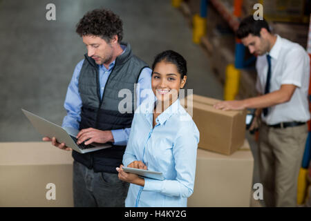 Warehouse workers using laptop and digital tablet Stock Photo