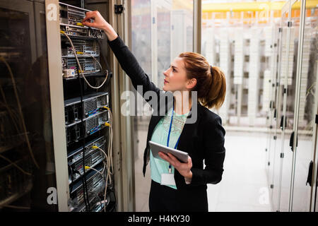 Technician holding digital tablet while examining server Stock Photo