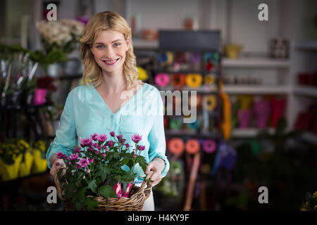 Happy female florist holding basket of flowers Stock Photo - Alamy