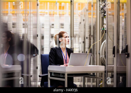Technician using laptop while analyzing server Stock Photo