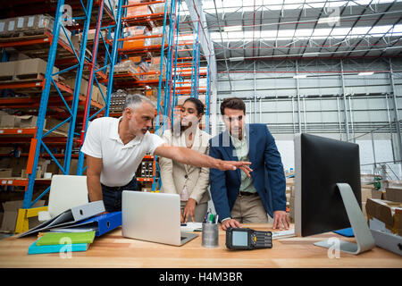 Warehouse managers and worker discussing with computer Stock Photo