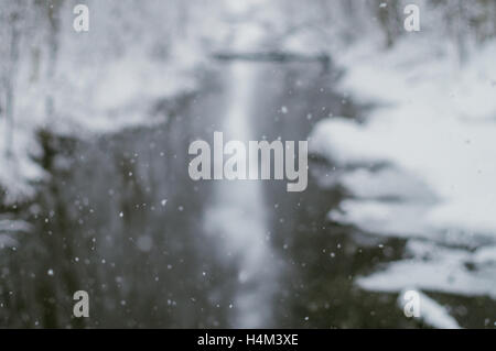 Defocused image of natural falling snow against river Stock Photo