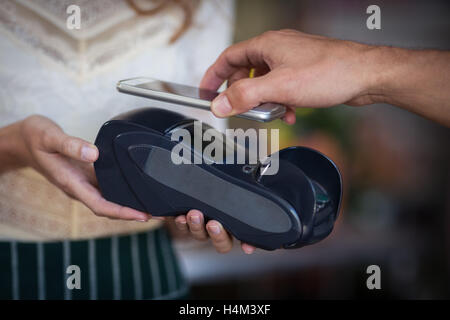 Hand of customer making payment through smartphone Stock Photo